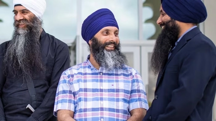 Hardeep Singh Nijjar entouré de deux hommes à la sortie d'un temple.